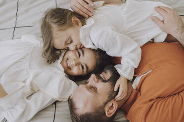 Glücklicher Vater umarmt süße Töchter auf dem Bett zu Hause - VBUF00289