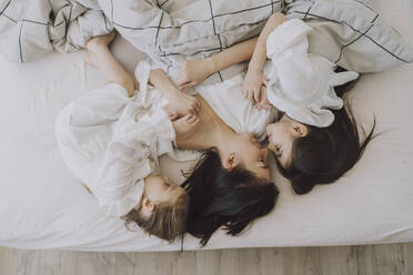 Happy mother and daughters in bed - VBUF00291