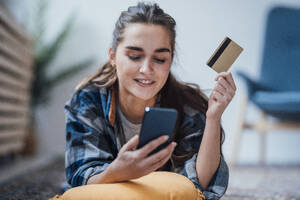 Lächelnde Geschäftsfrau mit Smartphone und Kreditkarte in der Hand - JOSEF18397