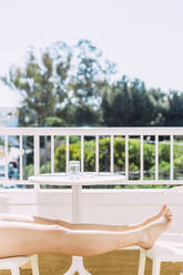 Frau entspannt auf dem Balkon an einem sonnigen Tag - EGHF00739