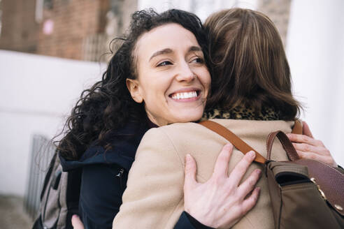 Happy niece embracing aunt outside building - AMWF01285