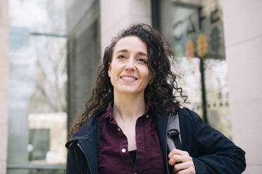 Thoughtful young woman standing outside building - AMWF01287