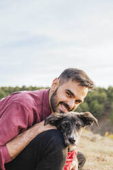 Glücklicher Mann mit Hund hockend - MGRF00927