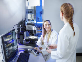 Lächelnde Wissenschaftlerin im Gespräch mit einem Techniker im E-Labor - CVF02373