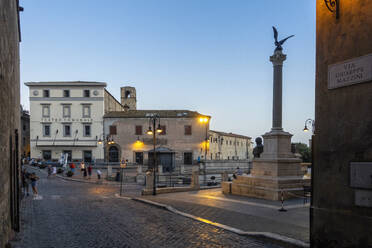 Italien, Latium, Tarquinia, Piazza Cavour in der Abenddämmerung mit Monumento a Giuseppe Mazzini und Teatro Comunale Rossella Falk im Hintergrund - MAMF02798