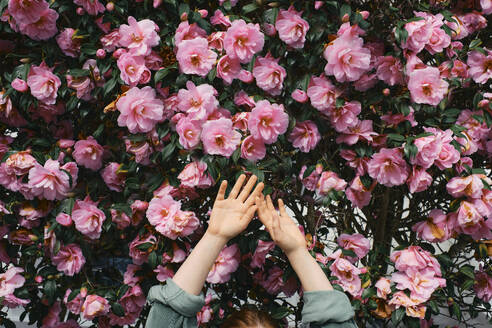 Woman with arms raised in front of flowers - ASGF03542