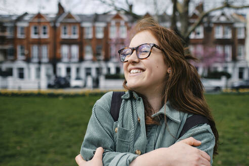 Cheerful young woman wearing eyeglasses hugging self - ASGF03549