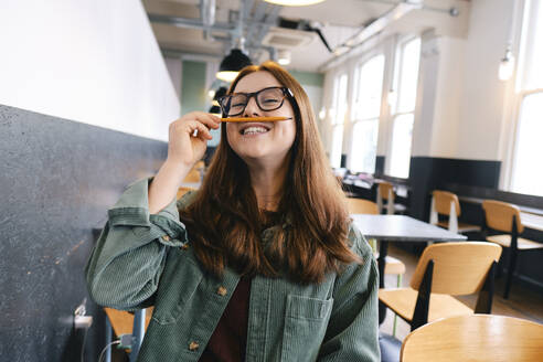 Playful freelancer holding pencil over lips - ASGF03555