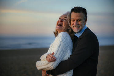 Fröhlicher Mann und Frau umarmen sich am Strand - EBSF03129