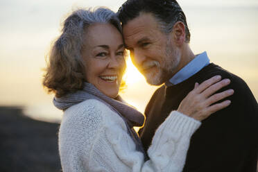 Lächelnde reife Frau und Mann umarmen sich bei Sonnenaufgang - EBSF03144