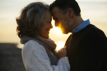 Lächelnde Frau umarmt Mann bei Sonnenaufgang - EBSF03146