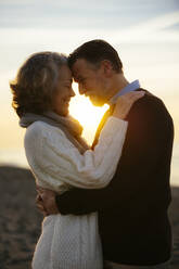 Glückliche reife Frau umarmt Mann bei Sonnenaufgang - EBSF03147