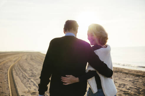 Lächelnde reife Frau mit Mann beim Spaziergang am Strand - EBSF03179