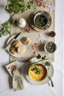 Studio shot of bowl of pumpkin soup with homemade buns in Christmas setting - EVGF04314