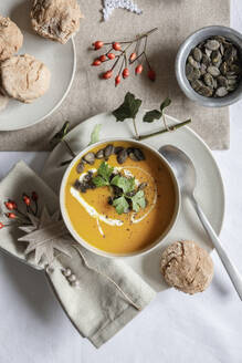 Studio shot of bowl of pumpkin soup with homemade buns in Christmas setting - EVGF04315