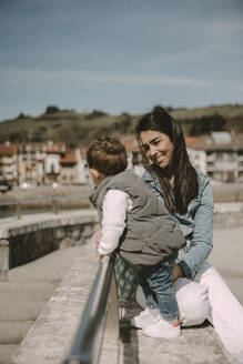 Happy mother sitting with son on sunny day - MTBF01265