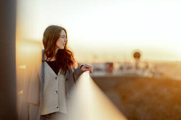 Woman with eyes closed standing by railing on bridge - ANAF01218