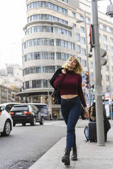 Woman holding leather jacket walking on sidewalk in city - JJF00752