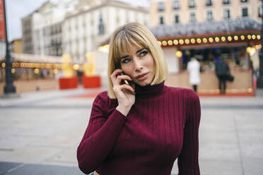 Nachdenkliche blonde Frau im Gespräch am Smartphone - JJF00766