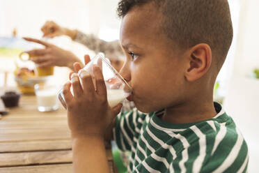 Boy drinking milk in glass at home - JCCMF10251