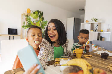 Ein fröhlicher Junge fängt einen besonderen Moment mit seiner Familie ein, während er das gemeinsame Frühstück in ihrem Haus genießt - JCCMF10259