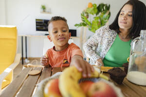 Junge frühstückt mit seiner Mutter am Esstisch - JCCMF10261