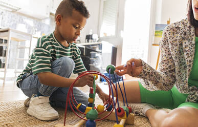 Mother assisting son in learning abacus at home - JCCMF10289