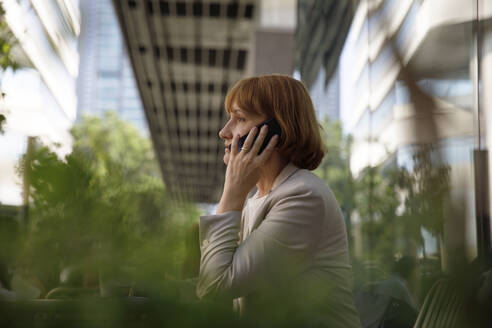 Mature businesswoman with brown hair talking on smart phone - IKF00090