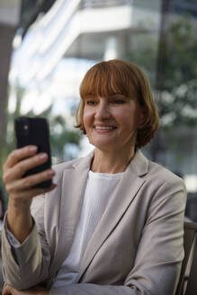 Lächelnde reife Geschäftsfrau mit Smartphone - IKF00092