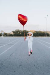 Mädchen zu Fuß in Parkplatz mit roten Herz Form Ballon - JCZF01235