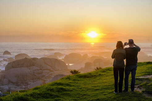 Südafrika, Westliche Kap-Provinz, Kapstadt, Touristen fotografieren den Atlantik bei Sonnenuntergang - LBF03811