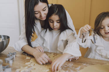 Mutter hilft Töchtern beim Backen von Keksen für Ostern - VBUF00305