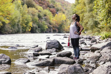 Frau mit Hand auf der Hüfte genießt die Natur am Fluss - JSRF02486