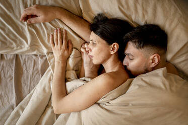 Man and woman snuggling in bed at home - ANAF01225