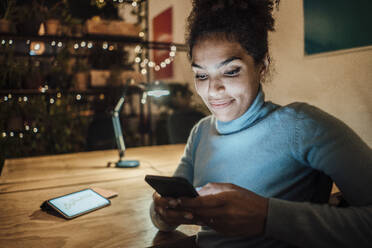 Smiling businesswoman surfing net using smart phone in office - JOSEF18456