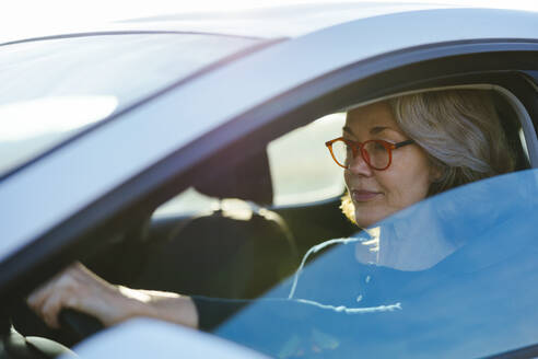 Mature woman wearing eyeglasses driving car - EBSF03180