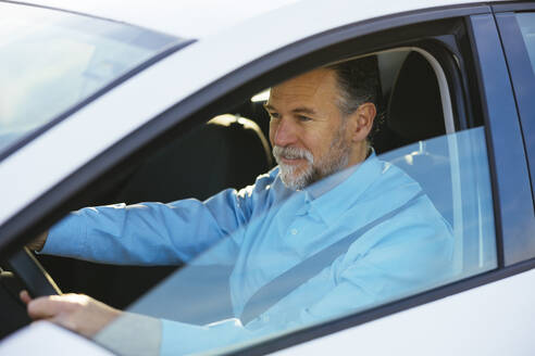 Älterer Mann am Steuer eines Autos durch ein Fenster gesehen - EBSF03192