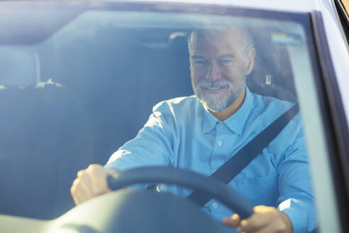 Lächelnder reifer Mann am Steuer eines Autos durch die Windschutzscheibe gesehen - EBSF03193