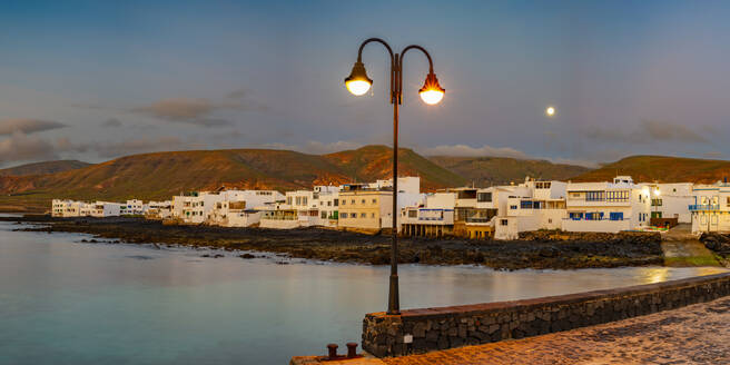 Spain, Canary Islands, Arrieta, Panoramic view of village on shore of Lanzarote island at dusk - WGF01458