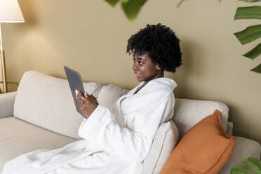Lächelnde Frau mit Tablet-PC auf dem Sofa zu Hause - AAZF00255
