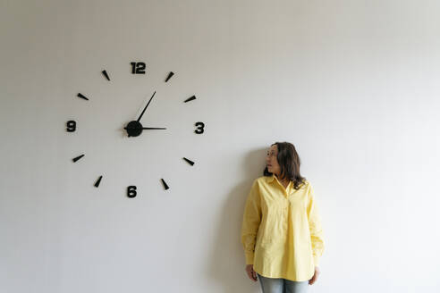 Woman looking at large clock on white wall - OSF01520