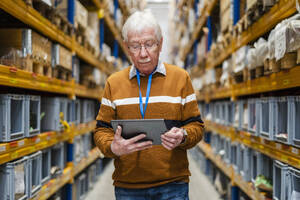 Senior man using tablet PC at warehouse - DIGF19880