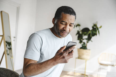 Älterer Mann benutzt Handy zu Hause - EYAF02600