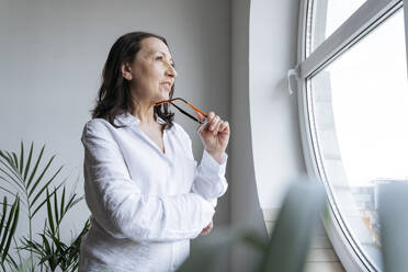 Thoughtful businesswoman standing near window - OSF01526