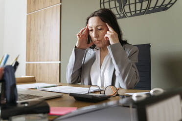 Worried businesswoman sitting at desk in office - OSF01536