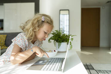 Blondes Mädchen tippt auf einem Laptop zu Hause - SVKF01373