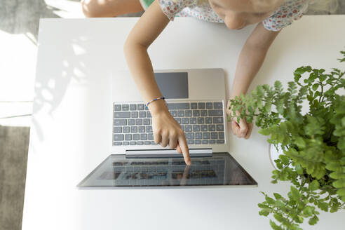 Mädchen berührt den Bildschirm des Laptops auf dem Tisch zu Hause - SVKF01377