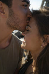 Young man kissing happy woman on forehead - IKF00131