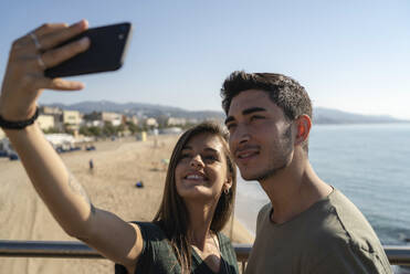 Ein glückliches Paar hält einen gemeinsamen Moment mit einem Selfie mit seinem Smartphone fest - IKF00134