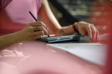 Hand einer Frau mit digitalisiertem Stift, die auf einem Grafiktablett zeichnet - IKF00149